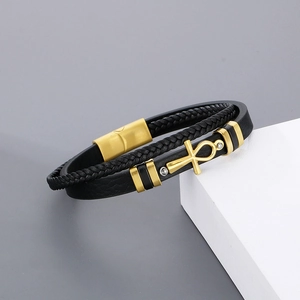 Detail of black woven leather men's bracelet with golden Ankh cross and magnetic clasp