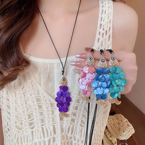 Detail of colorful shell fish pendants with evil eye design on black cords