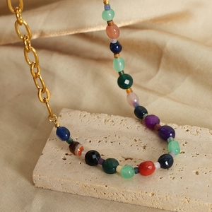 Collier de perles en agate naturelle et chaîne dorée en acier titane sur socle beige