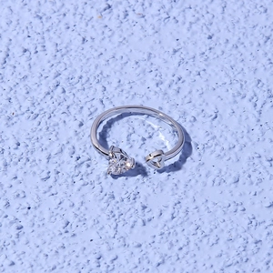 Detail shot of heart-shaped ring with a clear zircon and hollow heart on purple background
