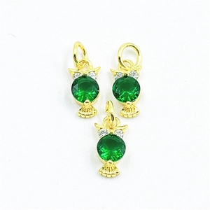 Macro detail of three owl pendants with green gemstones and gold-plated cubic zirconia