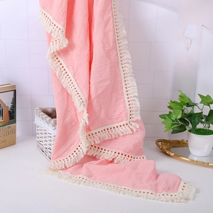 Detailed view of pink muslin baby blanket with fringe tassels and soft crinkle texture