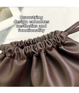 Close-up detail of dark brown leather bucket bag featuring a soft drawstring closure design