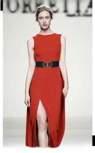 Close-up of black elastic waist belt with gold fan-shaped buckle on a red dress