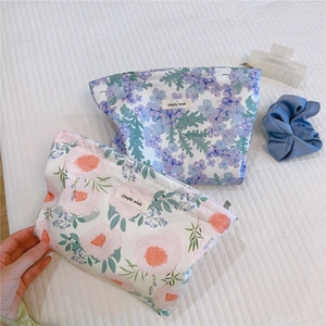 Detail of floral cotton makeup bags in pink and purple patterns with woven brand labels