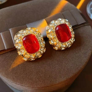 Makroaufnahme von Vintage-Ohrringen mit roten Harzsteinen und Kristallen in Gold