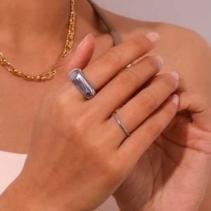 Gros plan sur des bagues en argent et un collier en chaîne dorée portés par un mannequin