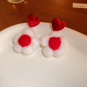 Detail of red and white flocked flower heart earrings on a ceramic plate for women