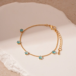Close-up of gold ball chain bracelet with five sky blue zircon stones and teardrop charm
