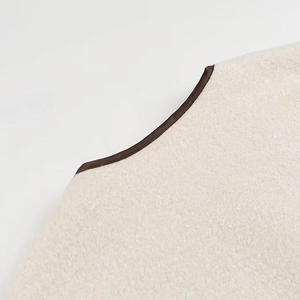 Close-up of cream textured faux fur fabric with premium dark brown piping trim detail
