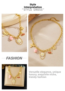 Macro detail of gold necklace featuring cherry, daisy, and butterfly charms set in a box