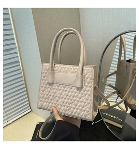 Gros plan du sac à main beige en cuir avec des textures gaufrées et une bandoulière