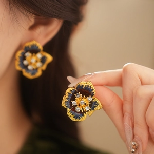 Macro detail of vintage gold flower earrings with blue enamel and white crystals