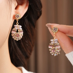 Close-up of pink and purple beaded drop earrings with golden accents on ear model