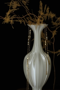 Detailed close-up of golden stainless steel star choker draped on a ceramic vase