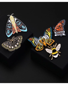 Detail of colorful butterfly and bee enamel pins with Anti-Social Butterfly text