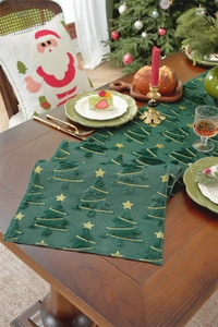 Detail of green Christmas table runner with embroidered trees and gold stars on wood