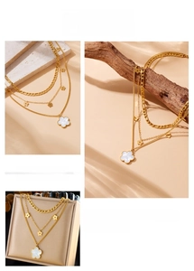 Detail of triple-layer gold necklace featuring clover pendants and shell texture finish