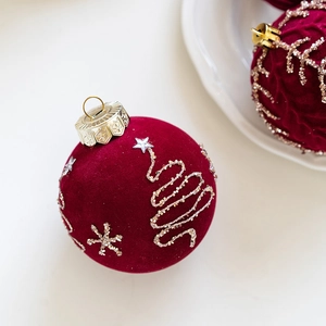 Close-up of 8cm burgundy flocked Christmas ball with gold glitter tree patterns