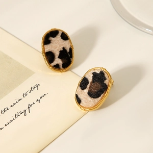 Detailed macro shot of oval 18K gold earrings featuring unique leopard print inserts