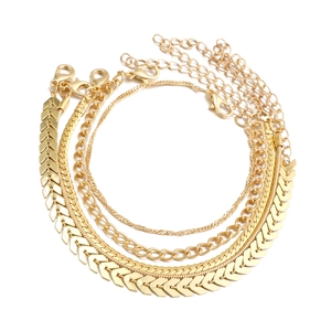 Detail of four gold-layered anklets with herringbone and snake chain designs on white background