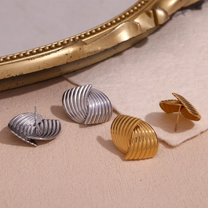 Detail of 18K gold and silver geometric earrings with spiral textured stripe design