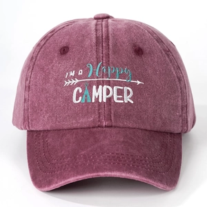 Close-up of I'M A Happy CAMPER embroidery on a washed dark red cotton baseball cap