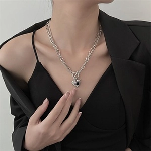 Close-up of silver heart pendant necklace with black gemstone and layered chain detail