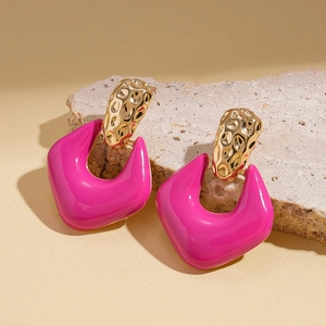Detail of geometric drop earrings with gold hammered metal and rose red resin on stone