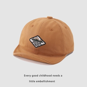 Detail of baby baseball cap with mountain embroidery on khaki cotton twill fabric
