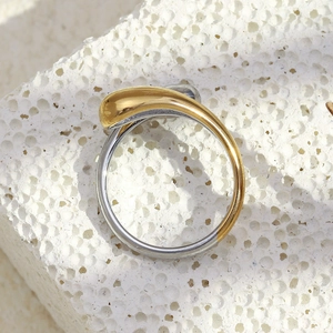 Detail of two-tone gold and silver snake head ring on textured white stone background