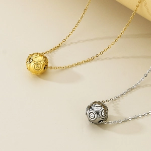 Detail of round ball pendants with circular textures in gold and silver stainless steel