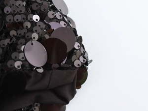 Macro shot of black sequins stitched on sheer mesh fabric for a sexy party dress
