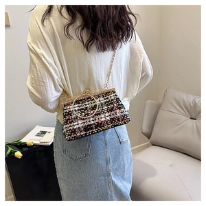 Crossbody sequin clutch bag with metal handle shown on a model in a minimal setting