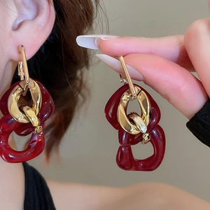 Close-up of vintage geometric acrylic tassel earrings with golden metal links on a model