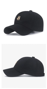 Macro detail of black cotton baseball cap featuring gold H letter embroidery and curved brim