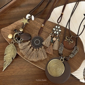Bohemian sweater necklaces with vintage feathers, tassels and wood beads on wood tray