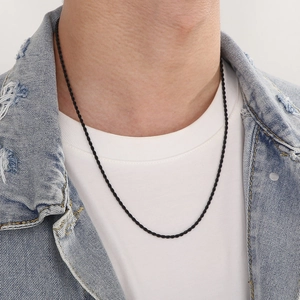 Detail of a black stainless steel rope twist chain worn by a model for a hip hop look