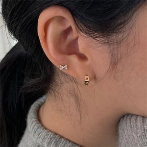 Close-up of heart hoop and bow stud earrings with sparkling crystals on model