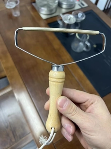 Close-up of manual lint remover with copper head and natural wooden handle for fabric care