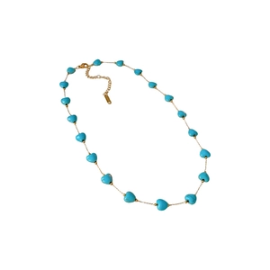Bohemian gold chain necklace with turquoise heart beads arranged on a clean white backdrop