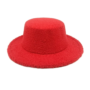 Macro shot of red faux shearling jazz hat showing thick fleece texture and flat brim
