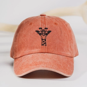 Detailed close-up of embroidered giraffe on rust red washed cotton baseball cap
