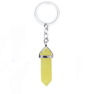 Detail view of a yellow hexagonal crystal pendant with silver metal keychain on white background