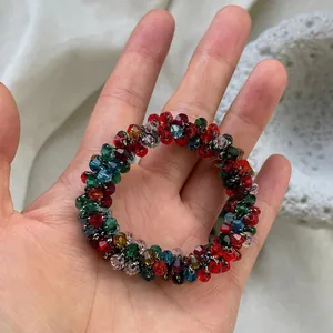 Hand holding colorful faceted crystal beaded elastic hair tie with vibrant spiral beads