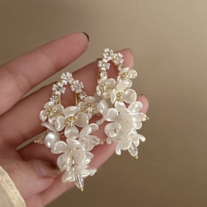 Detail of long tassel earrings with pearl-gloss flower petals and sparkling zircon accents