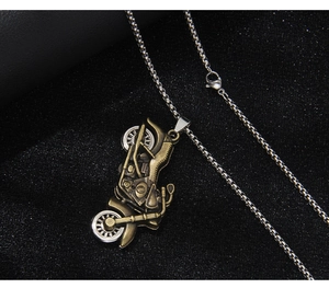 Close-up of vintage bronze motorcycle pendant with silver chain on dark textured background
