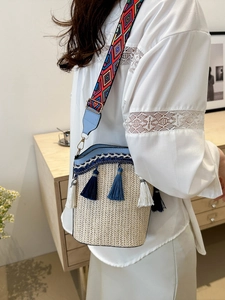 Detail of bohemian straw bucket bag with blue fringe and colorful geometric strap