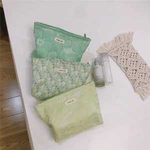 Flat lay of green floral jacquard canvas makeup bags with simple wish woven labels
