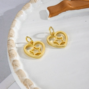 Macro detail of gold-plated hollow heart and star pendants on a ceramic tray